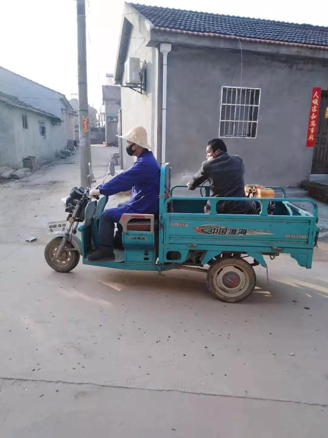王文明和村里的卫生员骑行三轮车前往消毒点位